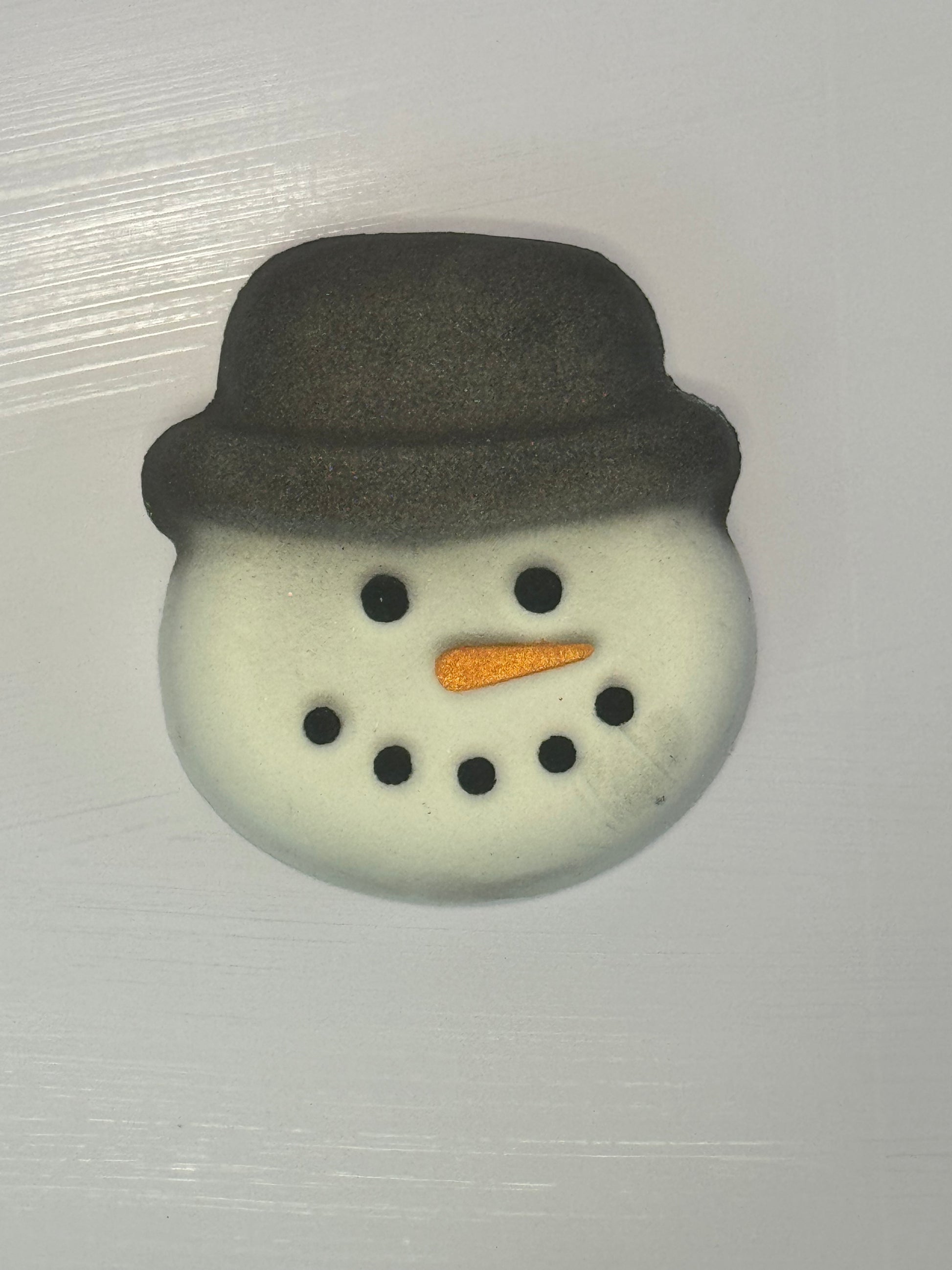 A snowman face bathbomb with a black top hat